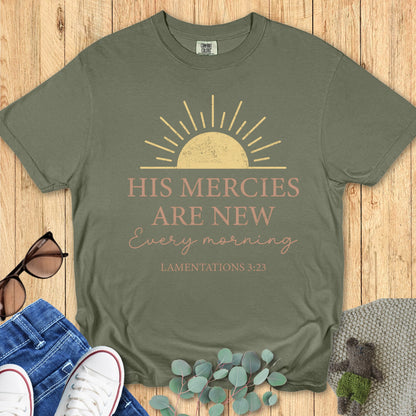Flatlay of a Comfort Colors 1717 sage green t-shirt reading “His Mercies Are New Every Morning – Lamentations 3:23.” A soft, vintage piece from women’s scripture tees collection, perfect as a Christian mom gift idea.