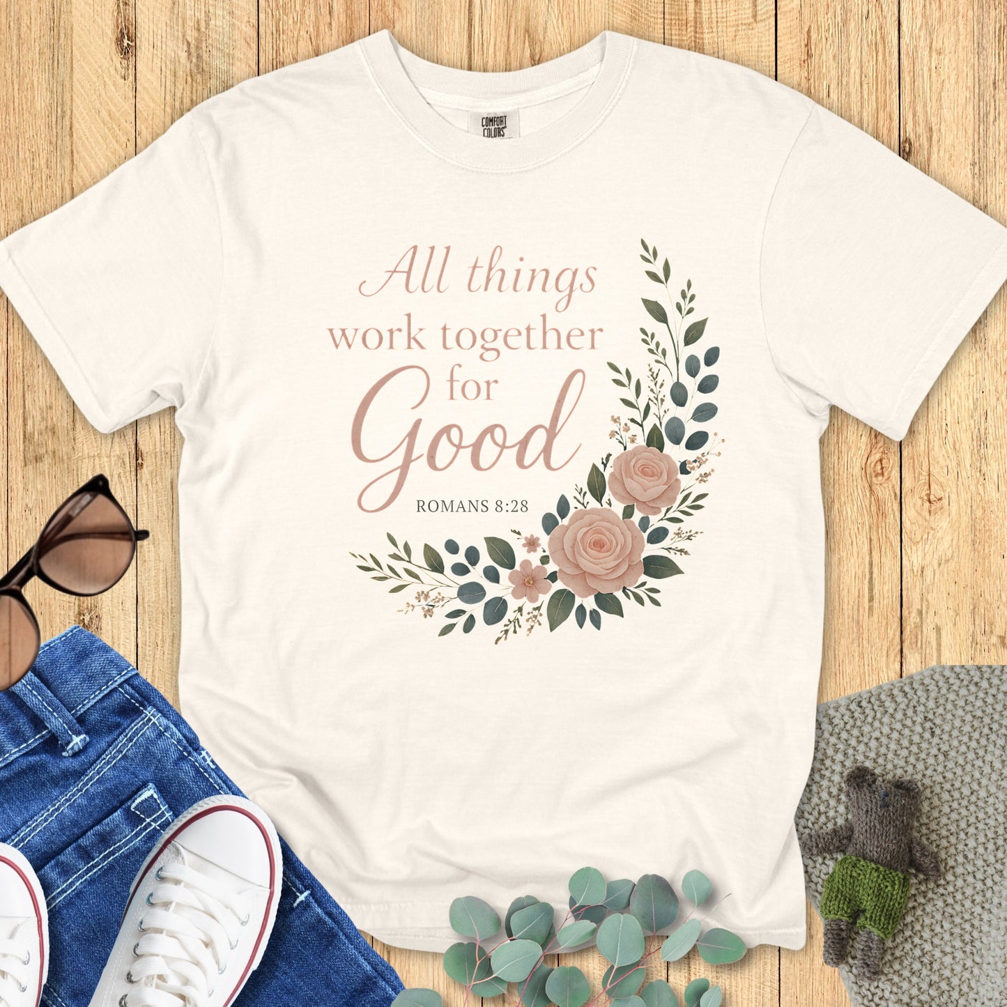 Comfort Colors 1717 ivory “All Things Work Together for Good – Romans 8:28” t-shirt flatlay with jeans and sunglasses. A timeless faith-based apparel for women design with elegant floral accents.