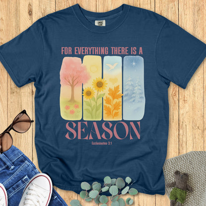 Flatlay of a Comfort Colors 1717 midnight “For Everything There Is a Season – Ecclesiastes 3:1” t-shirt featuring pastel illustrations of all four seasons. A colorful and uplifting women’s scripture tee and faith-based apparel for women.