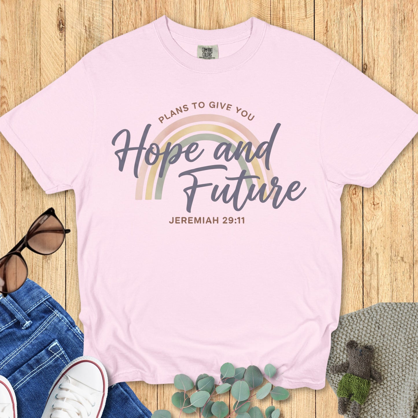 Flatlay of a Comfort Colors 1717 blossom “Hope and Future – Jeremiah 29:11” t-shirt featuring soft pastel rainbow tones. A feminine and hopeful women’s scripture tee — beautiful faith-based apparel for women and an inspiring Christian mom gift idea.