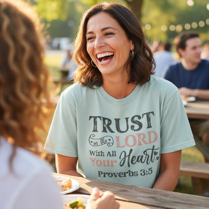 Smiling woman wearing a Comfort Colors 1717 bay “Trust in the Lord with all your heart – Proverbs 3:5” t-shirt while chatting outdoors. A joyful and uplifting women’s scripture tee — modern Christian shirt and faith-based apparel for women, perfect Christian mom gift idea.