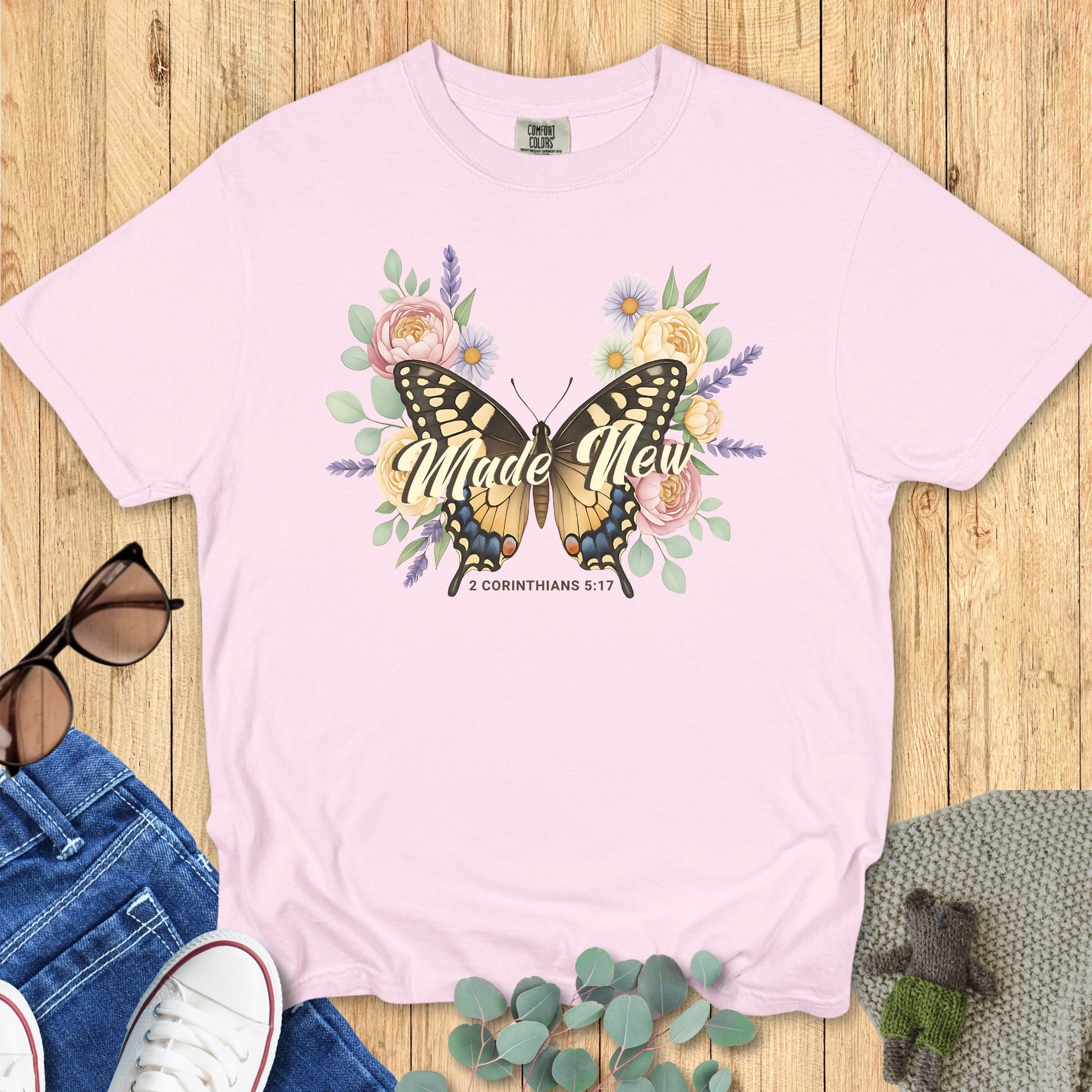 Comfort Colors 1717 blossom “Made New – 2 Corinthians 5:17” t-shirt with butterfly and pastel flower design symbolizing new life. A soft and feminine women’s scripture tee — inspiring faith-based apparel for women and thoughtful Christian mom gift.
