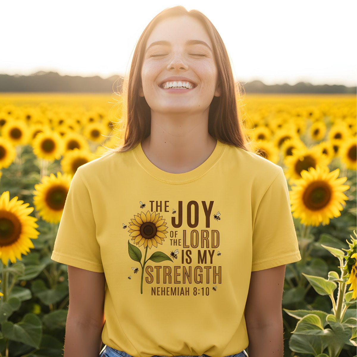 Smiling woman standing in a sunflower field wearing a Comfort Colors 1717 citrus “The Joy of the Lord Is My Strength – Nehemiah 8:10” t-shirt featuring a sunflower and bee design. A cheerful women’s scripture tee — modern Christian shirt and uplifting faith-based apparel for women, perfect Christian mom gift idea.