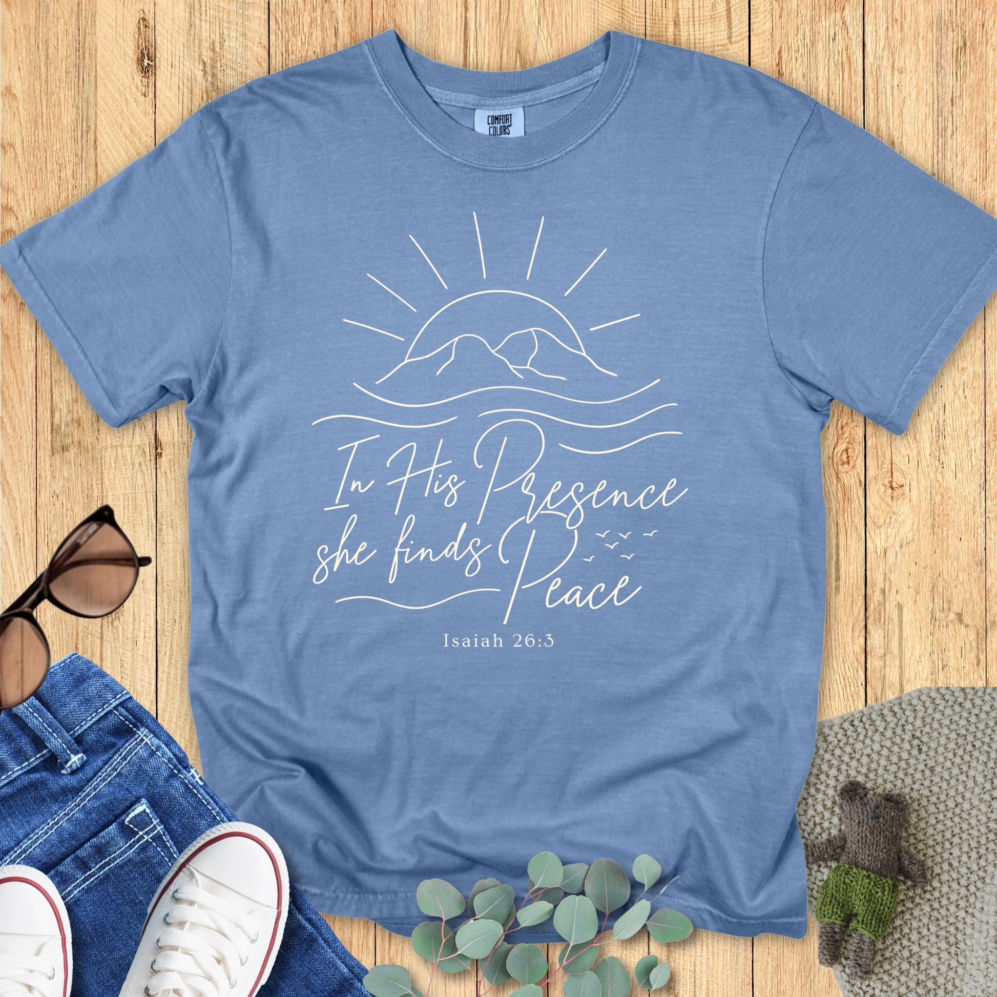 Comfort Colors 1717 blue jean “In His Presence She Finds Peace – Isaiah 26:3” t-shirt featuring sunrise over mountains graphic. A calm and uplifting women’s scripture tee — stylish faith-based apparel for women and thoughtful Christian mom gift.