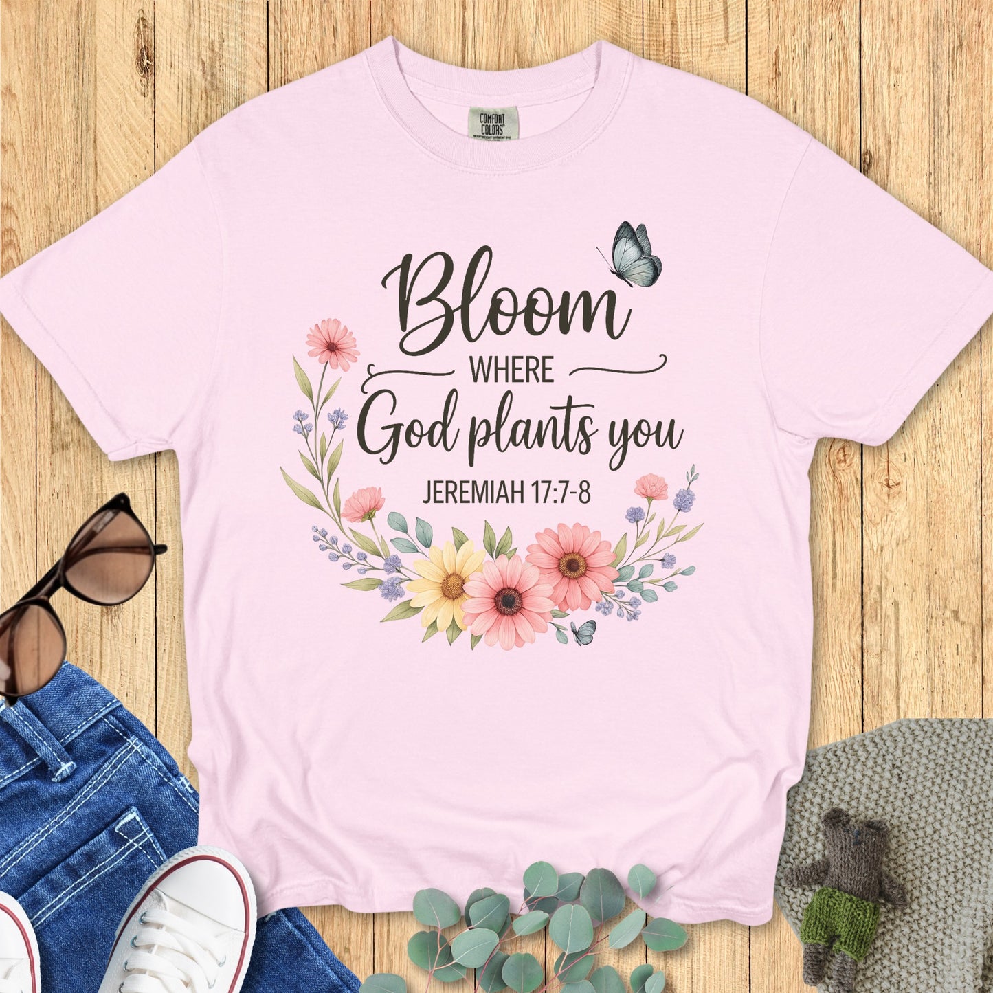 Flatlay of a Comfort Colors 1717 ivory “Bloom Where God Plants You – Jeremiah 17:7-8” t-shirt featuring pastel wildflowers and butterflies. A soft and feminine women’s scripture tee — modern Christian shirt and uplifting faith-based apparel for women, perfect Christian mom gift idea.