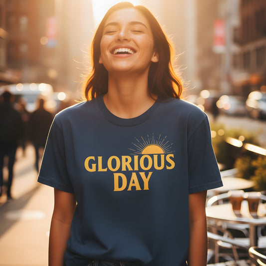 Woman smiling in the sunlight while wearing a Comfort Colors 1717 midnight “Glorious Day” t-shirt with a golden sunrise design. A joyful women’s scripture tee — uplifting faith-based apparel for women and modern Christian shirt, thoughtful Christian mom gift idea.