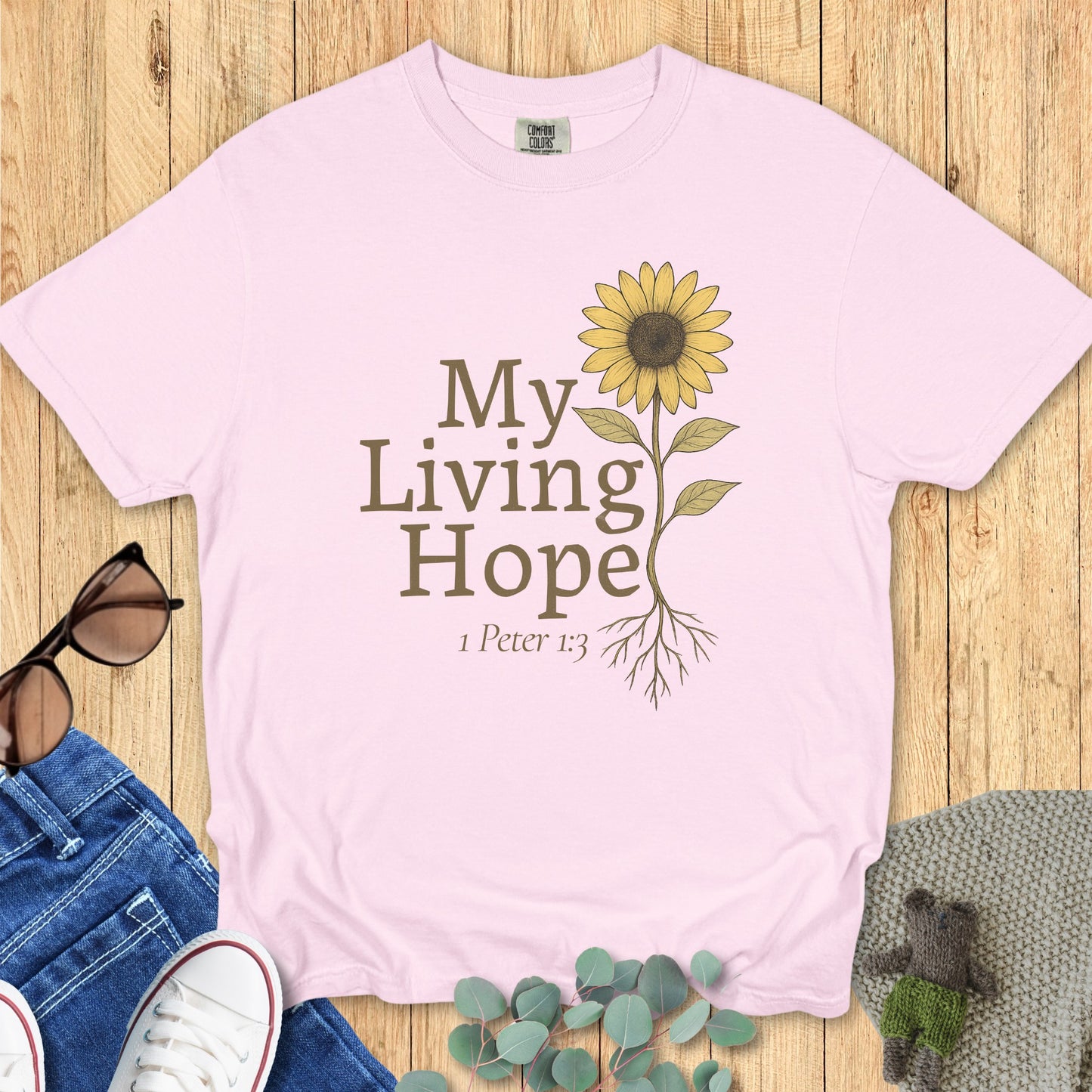 Flatlay of a Comfort Colors 1717 blossom “My Living Hope – 1 Peter 1:3” t-shirt with vintage-style sunflower illustration. A cheerful women’s scripture tee — uplifting faith-based apparel for women and modern Christian shirt, meaningful Christian mom gift idea.
