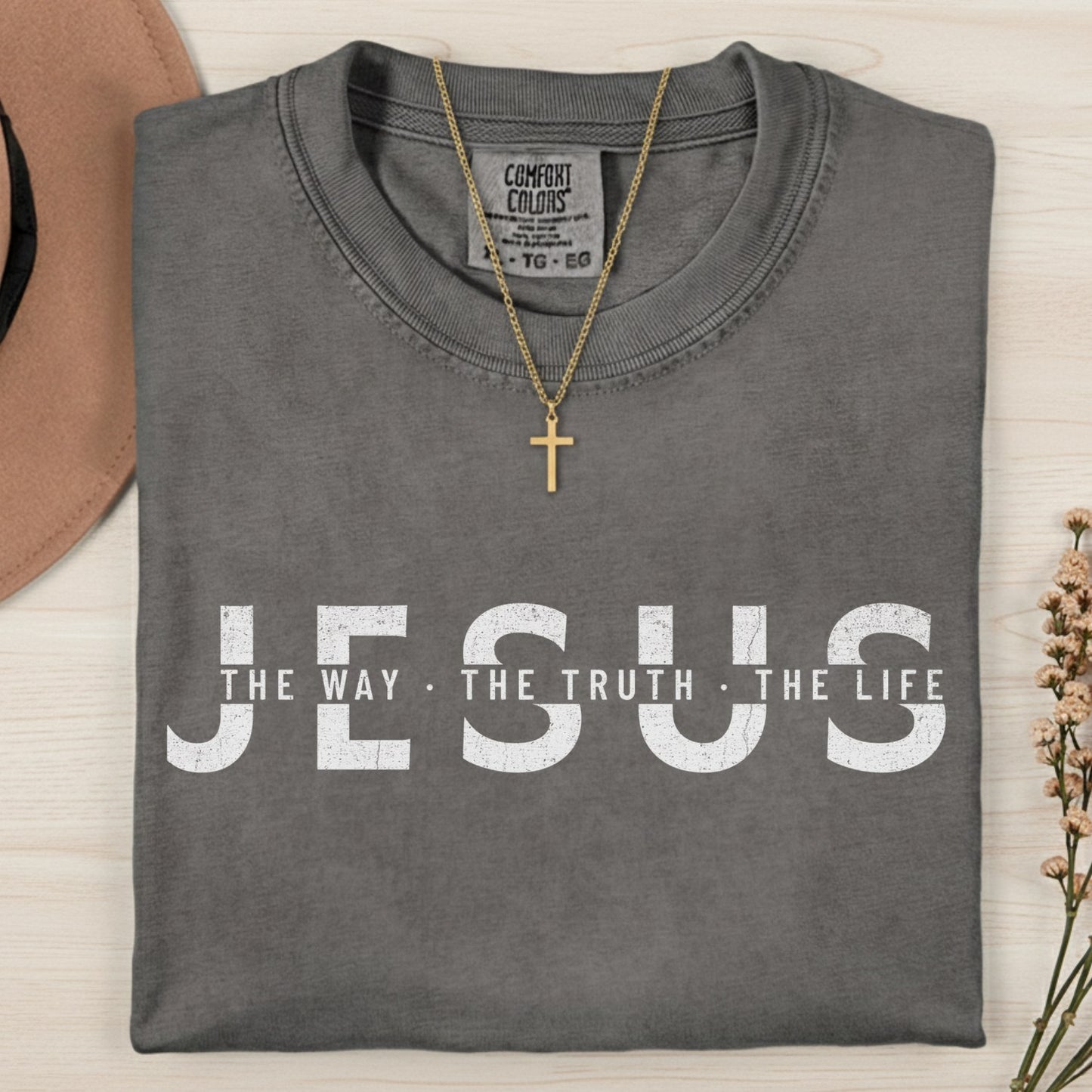 Folded Comfort Colors 1717 pepper “Jesus — The Way, The Truth, The Life” t-shirt with minimalist white distressed text. A timeless women’s scripture tee — faith-based apparel for women and modern Christian shirt inspired by John 14:6, meaningful Christian mom gift idea.