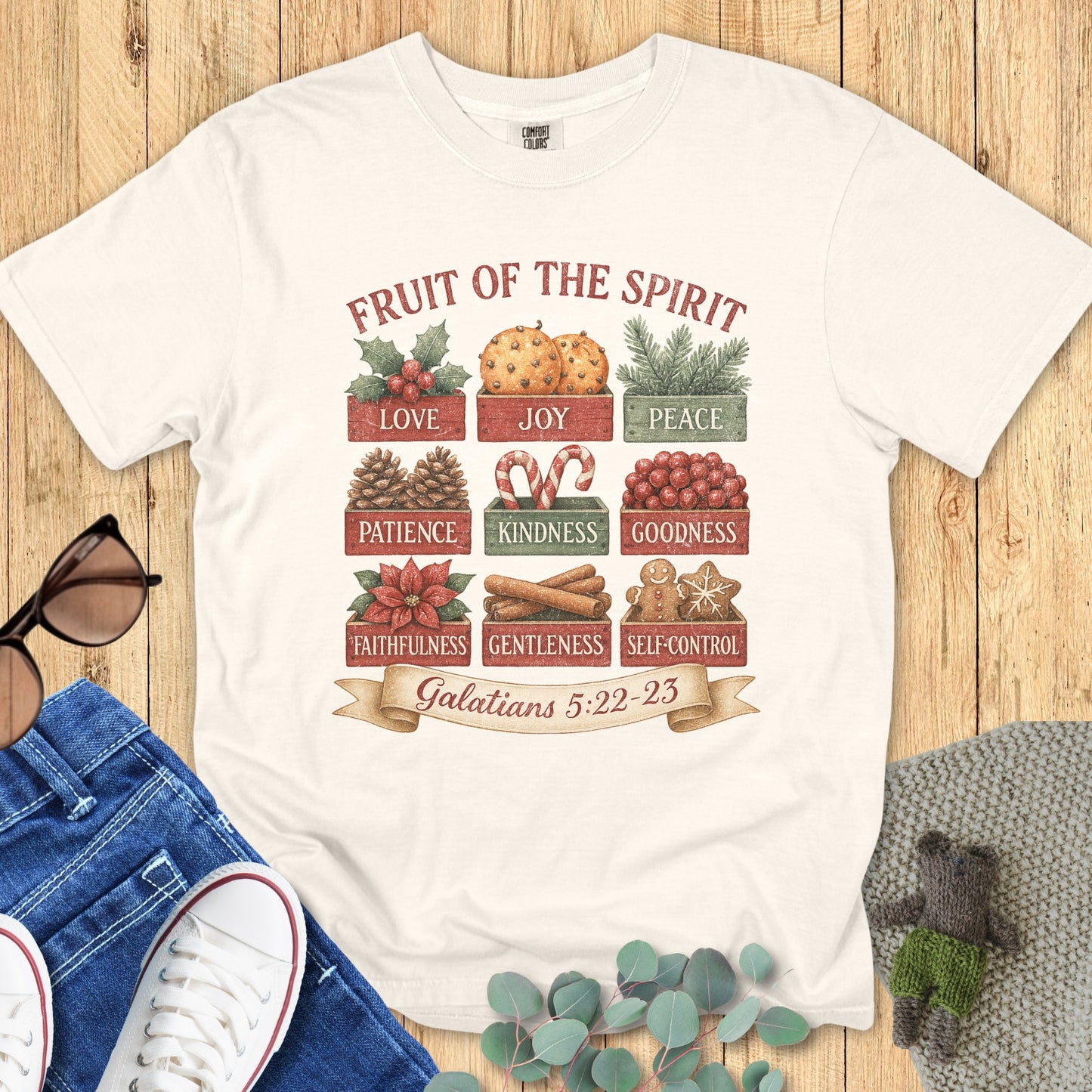 Flatlay of a Comfort Colors 1717 ivory “Fruit of the Spirit” t-shirt displaying a vintage Christmas-themed design with the nine fruits listed in Galatians 5:22–23. A timeless women’s scripture tee — faith-based apparel for women and modern Christian shirt, beautiful Christian mom gift idea.