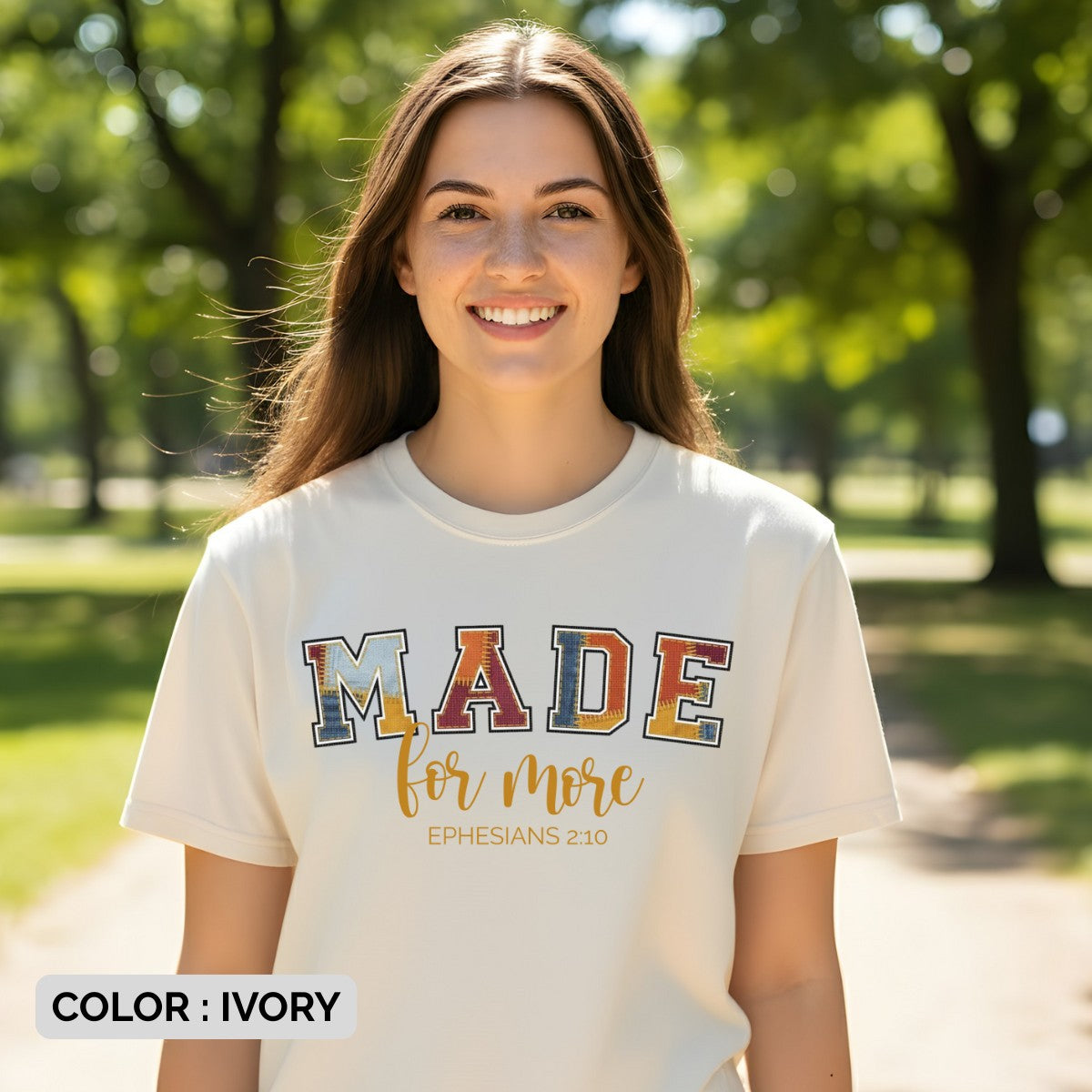 Woman smiling outdoors wearing a Comfort Colors 1717 ivory “Made for More” Ephesians 2:10 t-shirt with multicolor varsity patch lettering. A motivational women’s scripture tee - faith-based apparel for women and modern Christian shirt, meaningful Christian mom gift idea that inspires purpose.