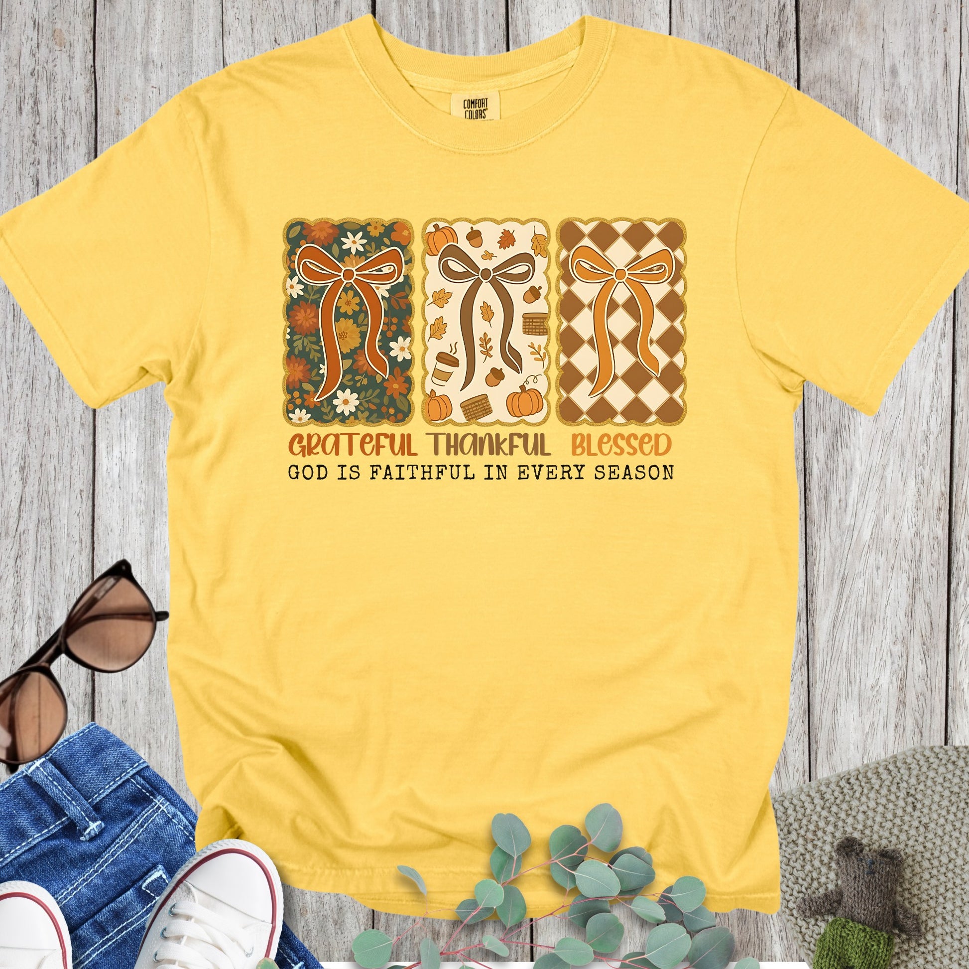 Flatlay of a Comfort Colors 1717 citrus “Grateful Thankful Blessed – God Is Faithful in Every Season” t-shirt with cheerful retro design and warm fall palette. A bright women’s scripture tee -  faith-based apparel for women and modern Christian shirt, sweet Christian mom gift idea reminding her of God’s faithfulness.