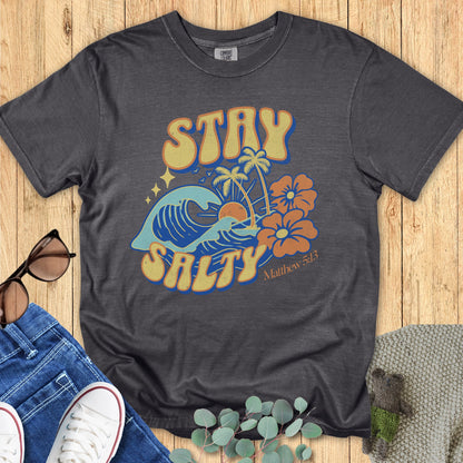 Flatlay of a Comfort Colors 1717 pepper “Stay Salty” t-shirt featuring retro beach graphics with waves, palms, and hibiscus flowers inspired by Matthew 5:13. A fun women’s scripture tee - faith-based apparel for women and modern Christian shirt, great Christian mom gift idea for summer.