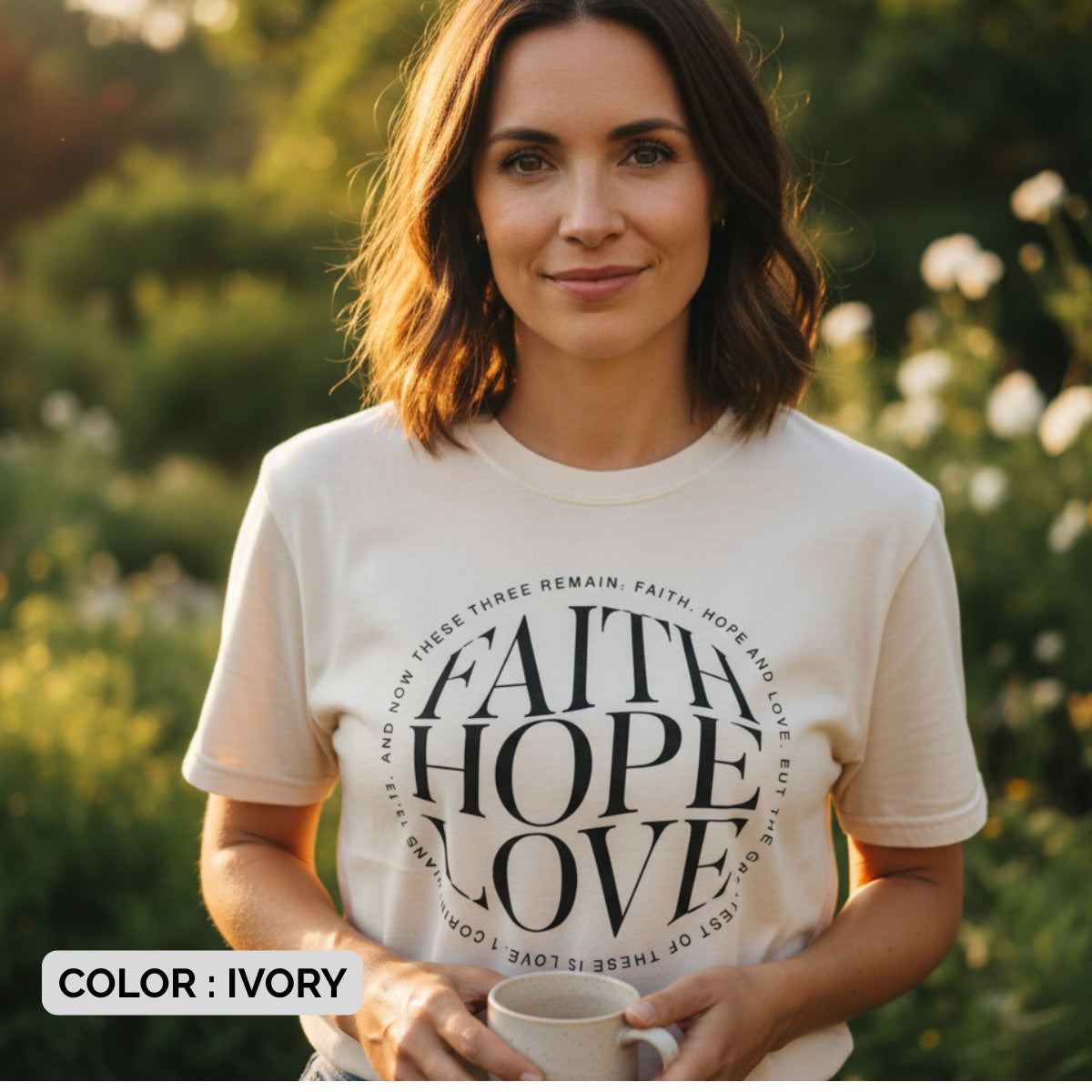 Woman wearing a Comfort Colors 1717 ivory “Faith Hope Love” t-shirt with 1 Corinthians 13:13 verse, standing outdoors in soft sunlight. A cozy women’s scripture tee - faith-based apparel for women and modern Christian shirt, perfect Christian mom gift idea for daily encouragement.