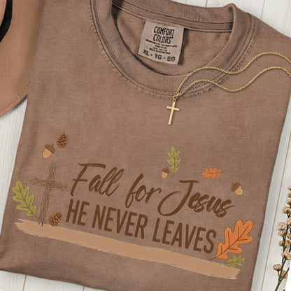 Flatlay of a Comfort Colors 1717 espresso “Fall for Jesus, He Never Leaves” t-shirt with autumn foliage and cross design. A soft women’s scripture tee -  faith-based apparel for women and modern Christian shirt, perfect Christian mom gift idea for cozy fall days.