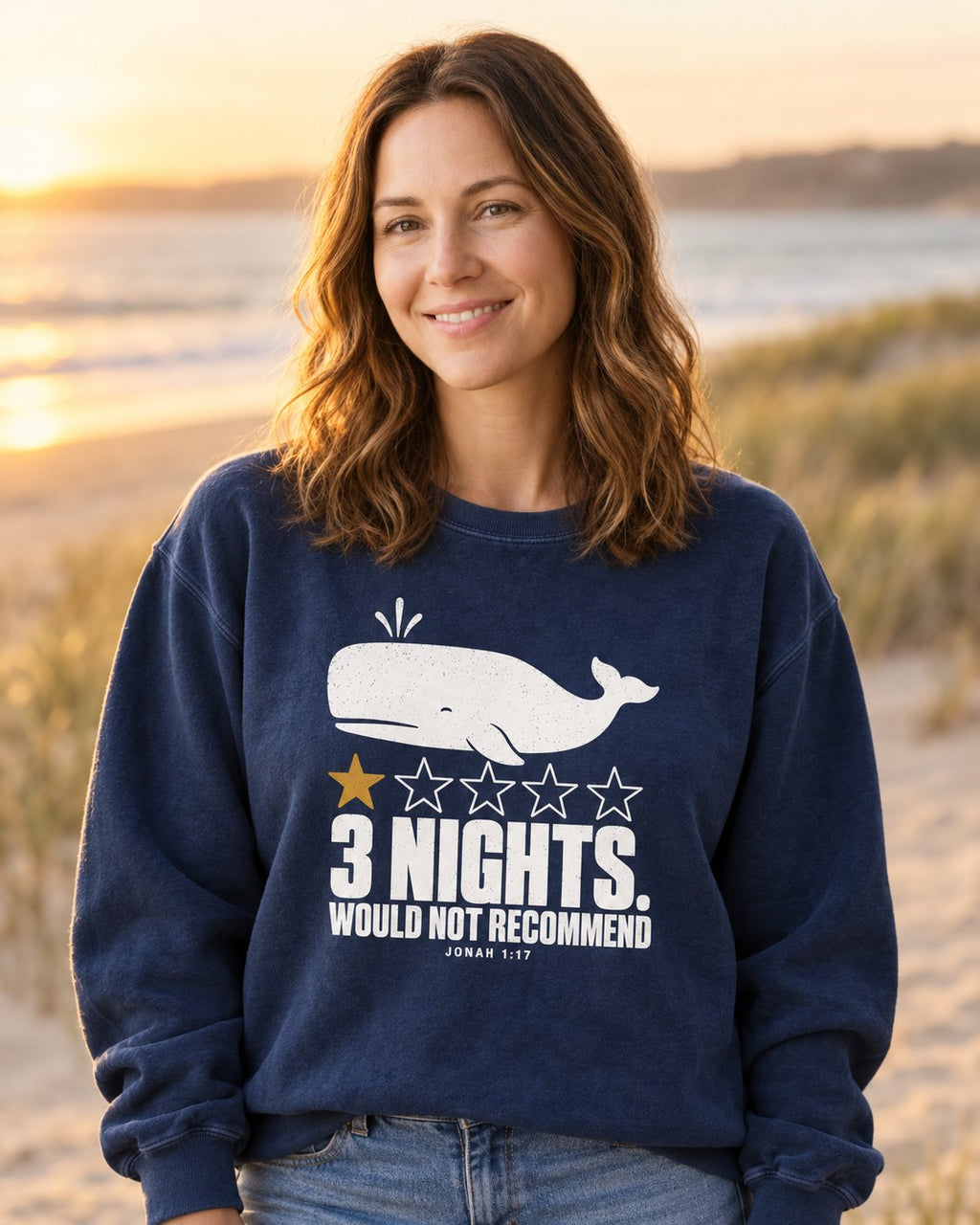 3 Nights Jonah 1:17, True Navy women's Christian sweatshirt, lifestyle photo in seaside setting, White whale with five stars and 3 NIGHTS WOULD NOT RECOMMEND, She Wears Faith