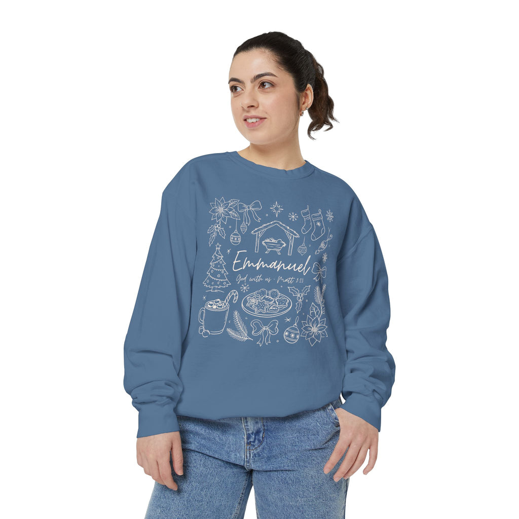 Christian Christmas sweatshirt with Emmanuel God with us script and Matthew 1:23 surrounded by doodles of a manger, stockings, a tree, cocoa and cookies.