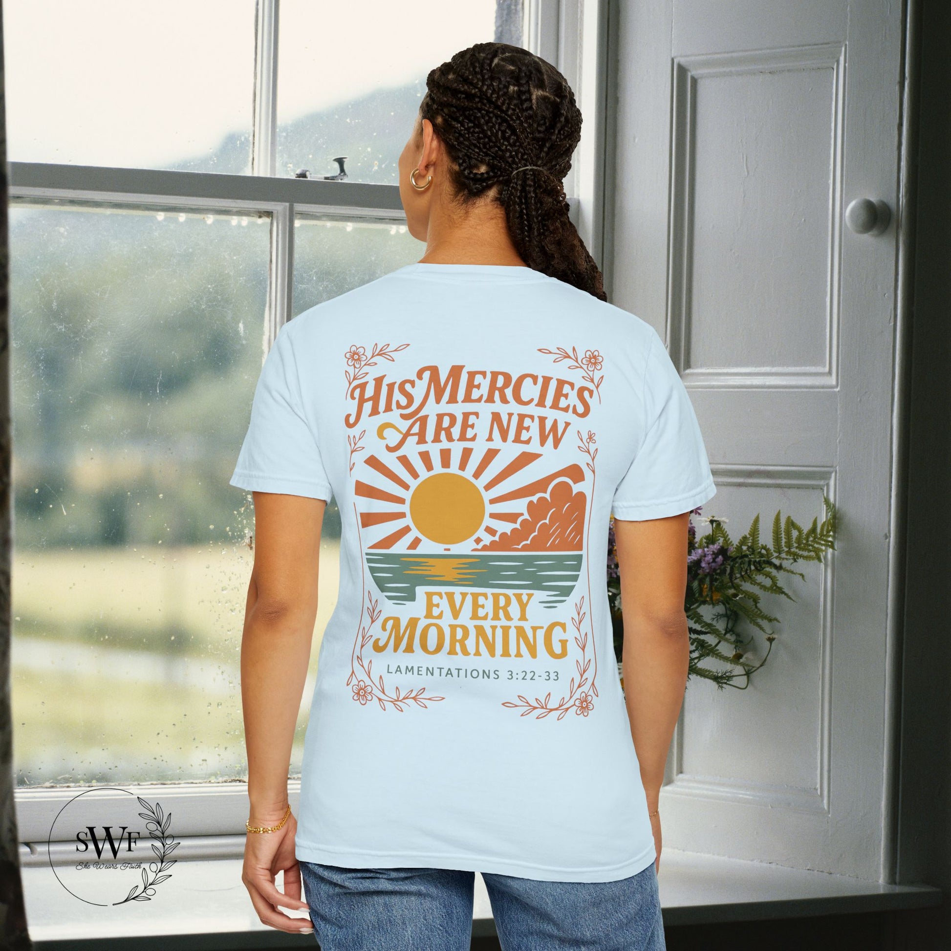 Back view of a soft blue chambray Christian t-shirt featuring a sunrise graphic and “His Mercies Are New Every Morning – Lamentations 3:22–33.”