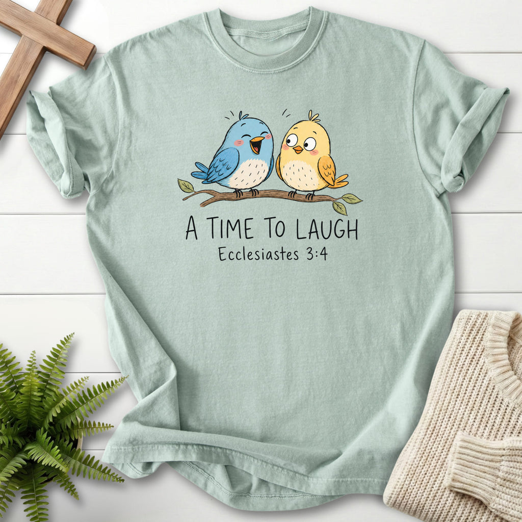 Flat lay of a Bay faith-based tee featuring "A Time To Laugh Faith Birds T-Shirt" Ecclesiastes 3:4.