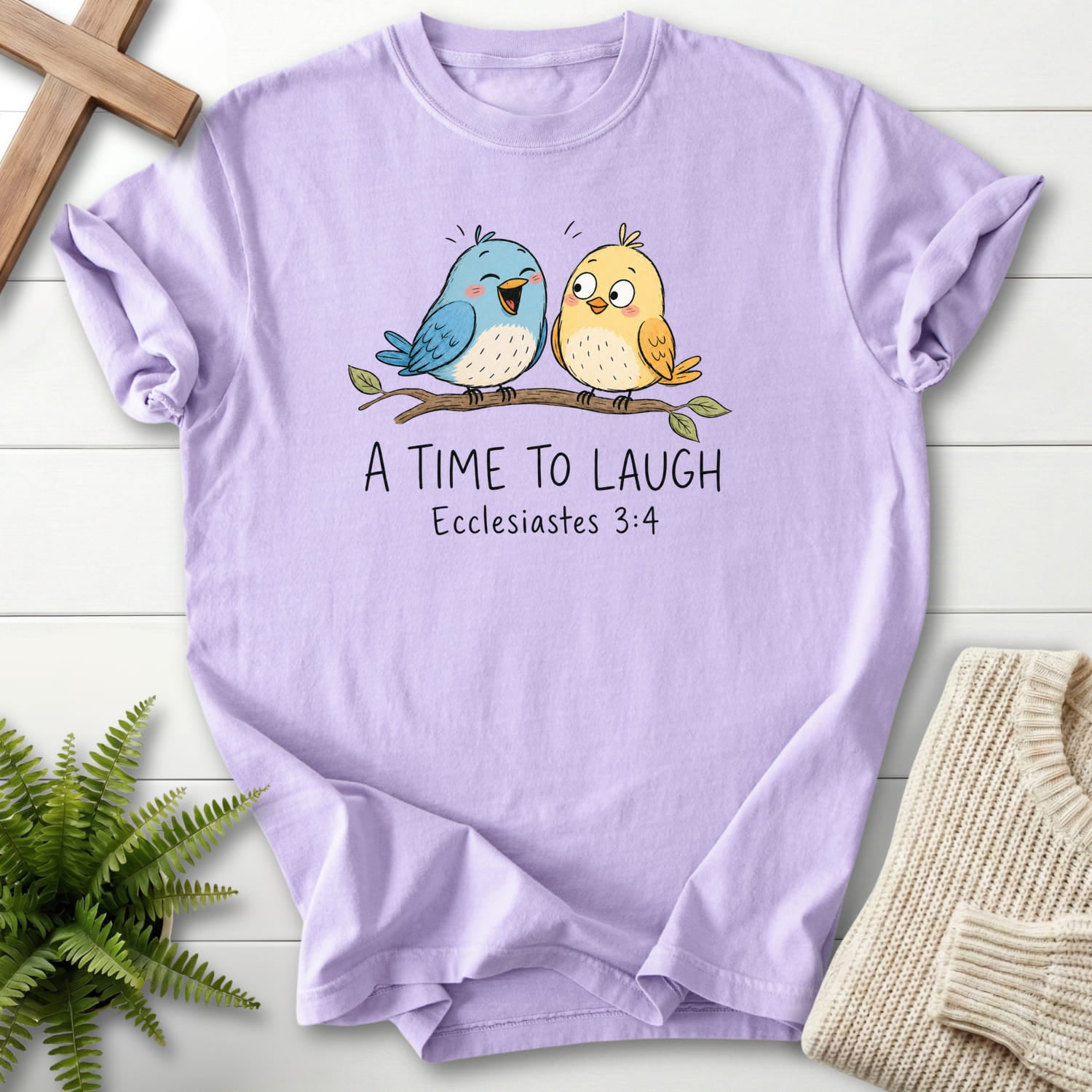 Flat lay of an Orchid women's Christian tee featuring "A Time To Laugh Faith Birds T-Shirt" Ecclesiastes 3:4.