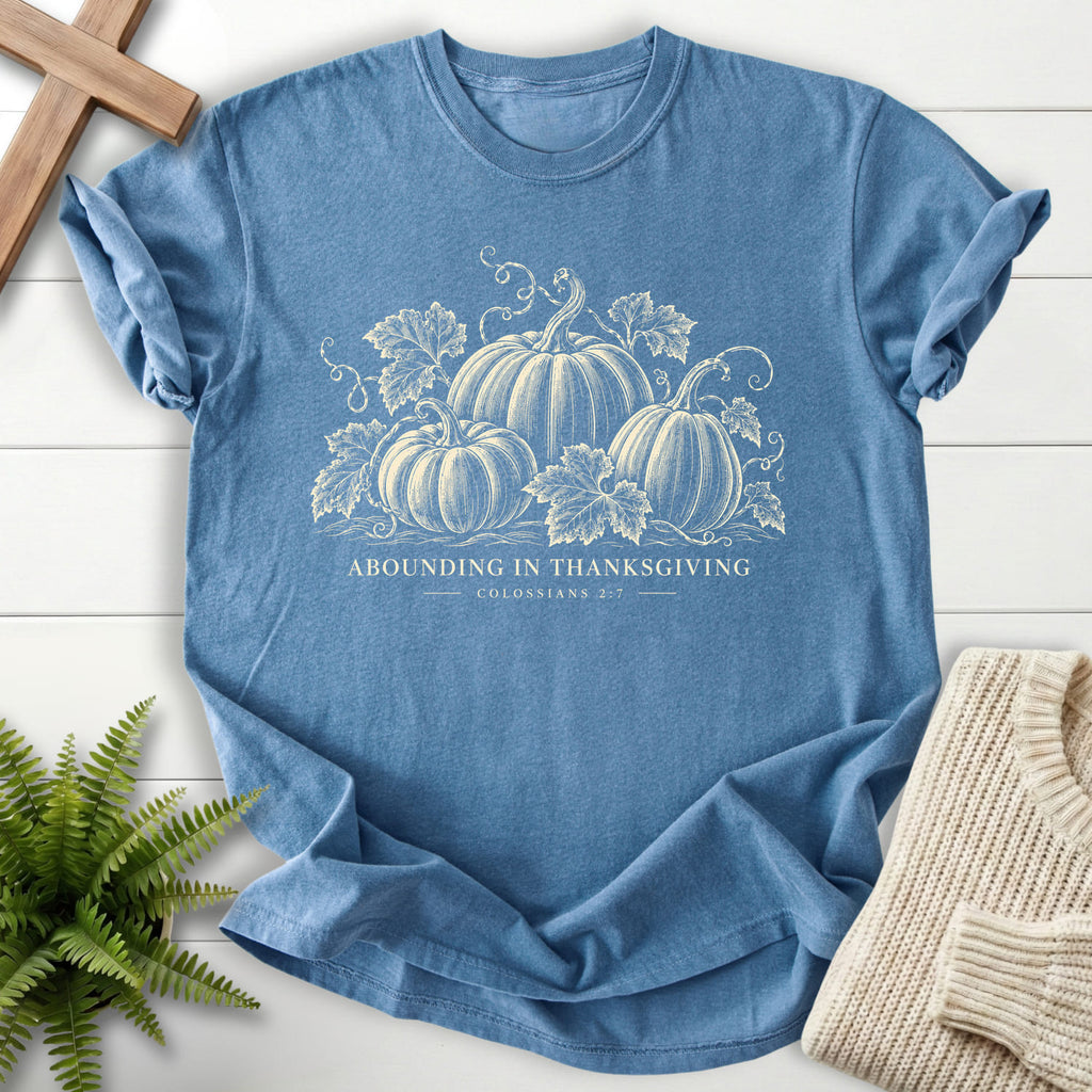 Flatlay of a Blue Jean Christian t-shirt for women with "Abounding in Thanksgiving T-Shirt" design.