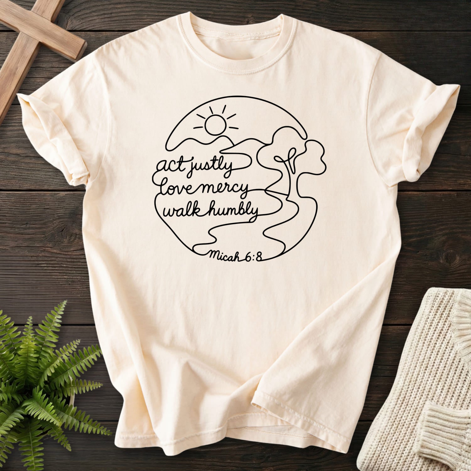 Flatlay of an Ivory faith-inspired shirt with sunrise graphic with "Act Justly Micah 6 8 Dark T-Shirt".