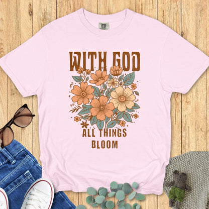 Christian women’s Comfort Colors 1717 t-shirt in Blossom pink with vintage-style florals and text ‘With God All Things Bloom.’ Flat lay styled with jeans, sunglasses, and cozy accents