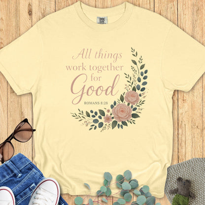 Flatlay of a Comfort Colors 1717 butter yellow “All Things Work Together for Good – Romans 8:28” t-shirt with floral artwork. A soft pastel piece from women’s scripture tees, perfect as a Christian mom gift idea.