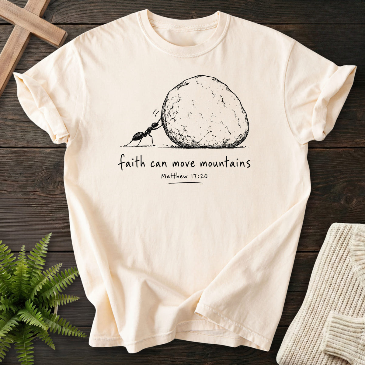 Flat lay of an Ivory Comfort Colors 1717 faith-based tee featuring "Ant and Boulder Faith T-Shirt" Matthew 17:20.