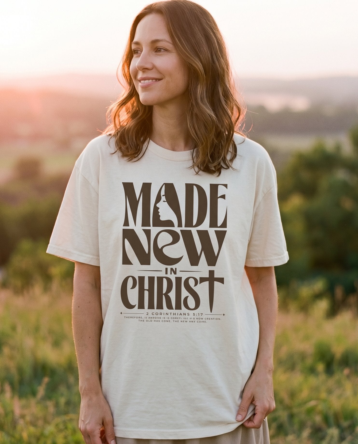 Made New in Christ – Ivory women's Christian tee, lifestyle photo in wildflower meadow at sunrise – Made New in Christ 2 Corinthians 5:17 new creation arise new morning t – She Wears Faith
