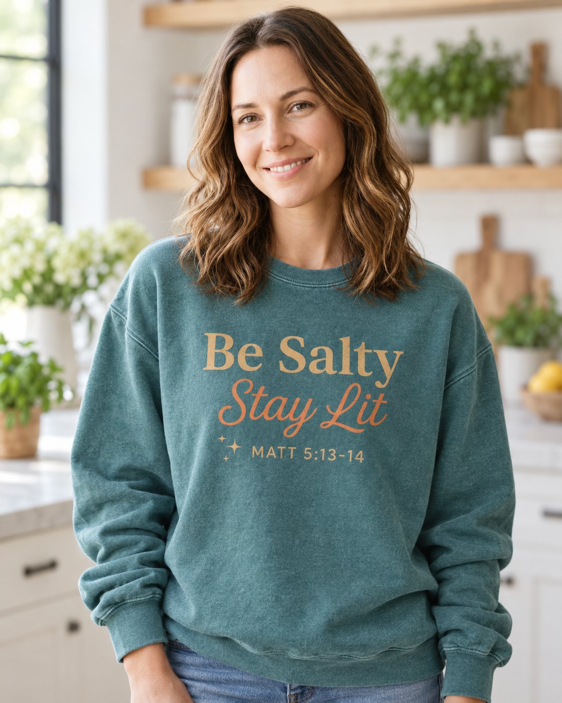 Be Salty Stay Lit – Blue Spruce women's Christian sweatshirt, lifestyle photo in morning kitchen setting – Gold Be Salty Stay Lit script with small stars – She Wears Faith