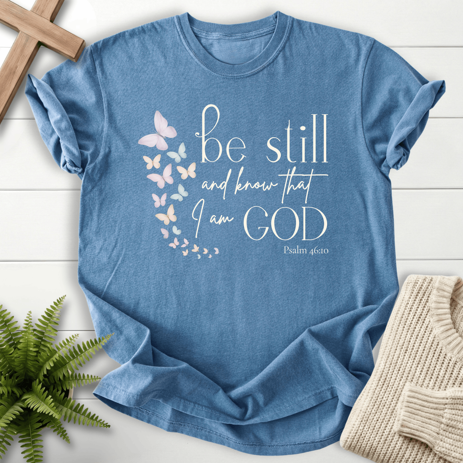 Blue Jean Christian t-shirt for women with pastel butterfly artwork and 'Be Still and Know That I Am God', inspired by Psalm 46:10.