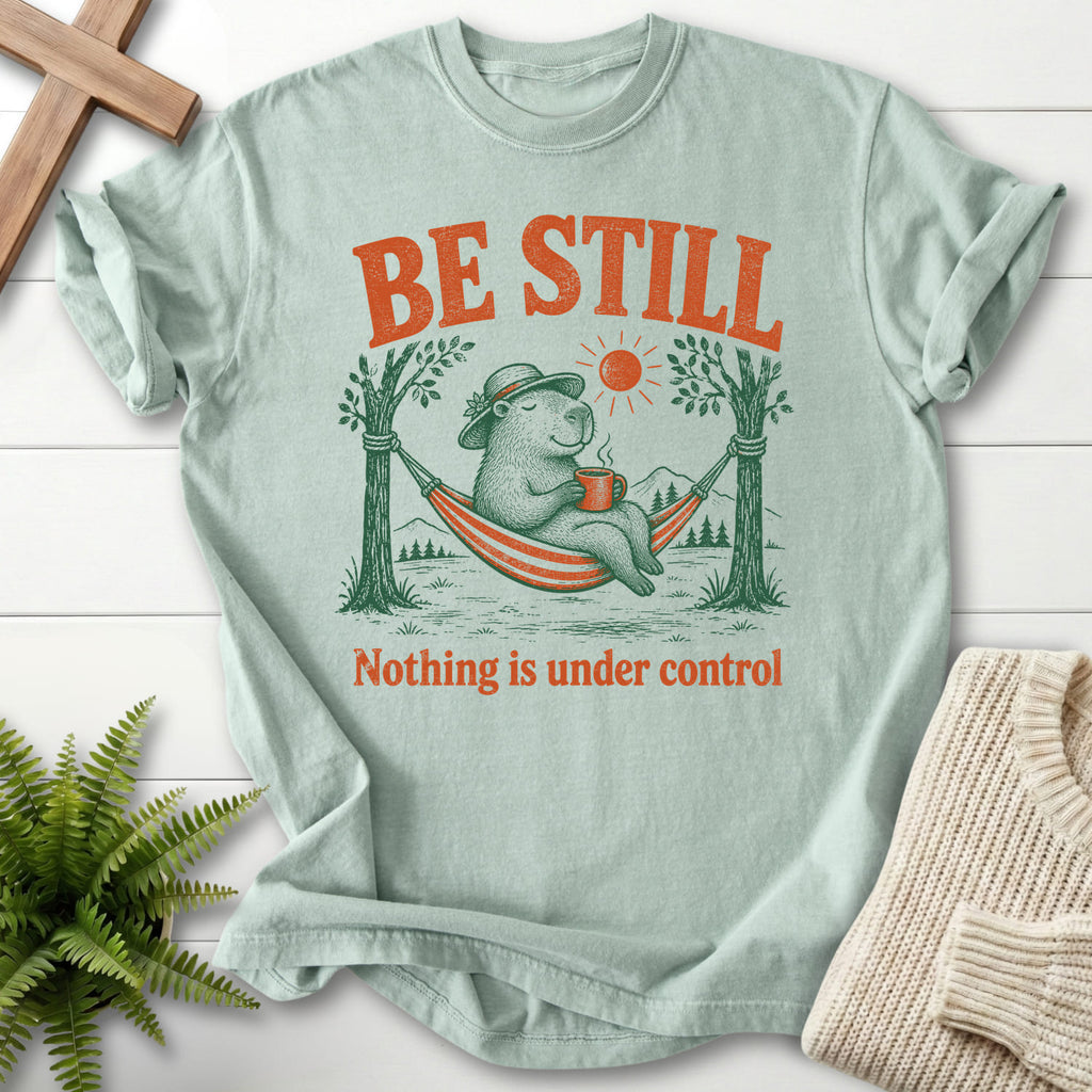 Flat lay of a Bay Christian shirt featuring capybara hammock graphic with "Be Still Capybara T-Shirt".