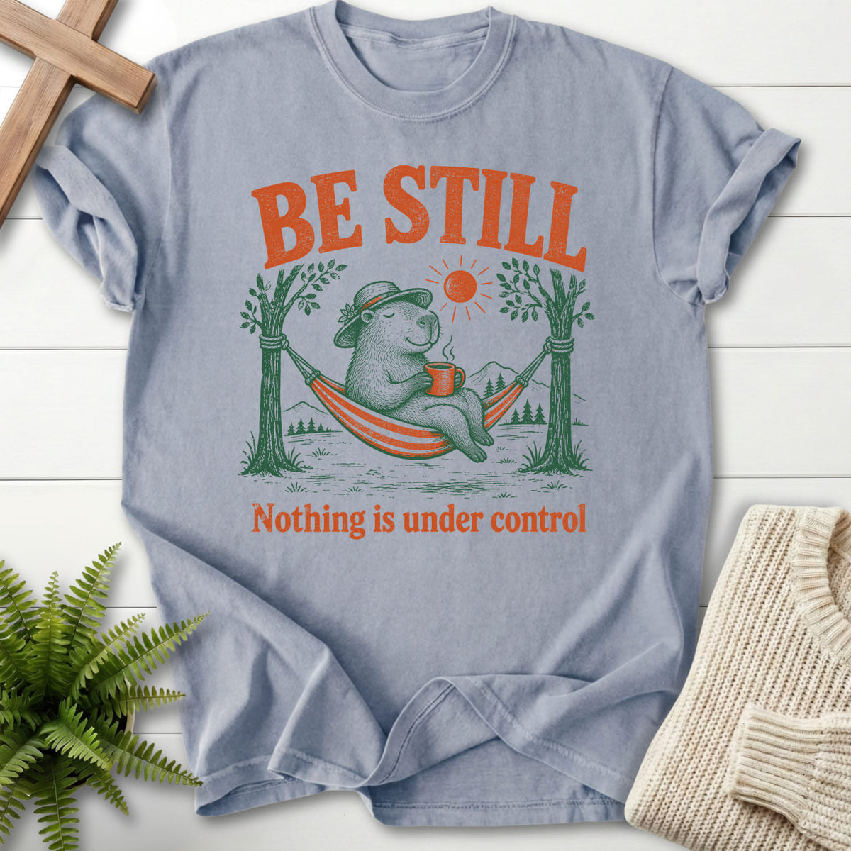 Flatlay of a Granite Christian t-shirt for women with capybara hammock graphic with "Be Still Capybara T-Shirt".