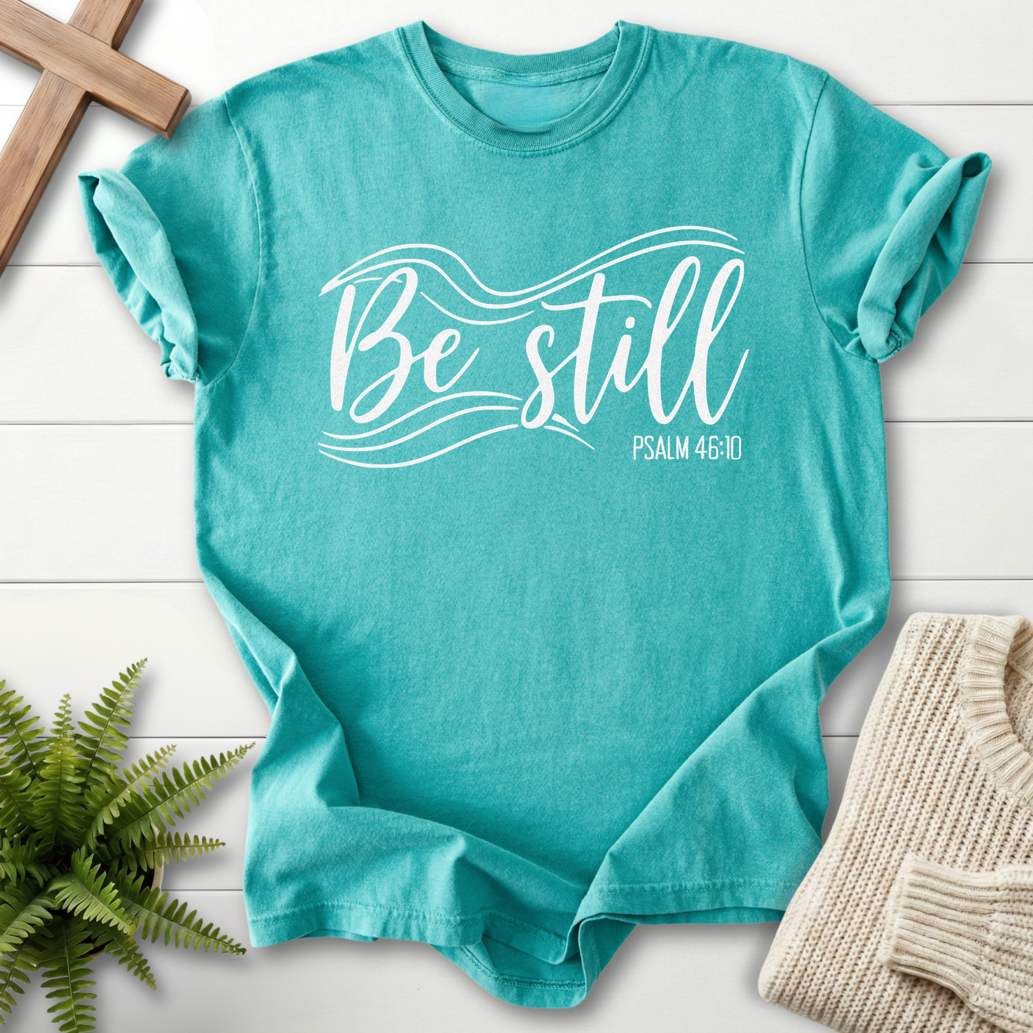 Seafoam Christian t-shirt for women with flowing 'Be Still' script, inspired by Psalm 46:10.