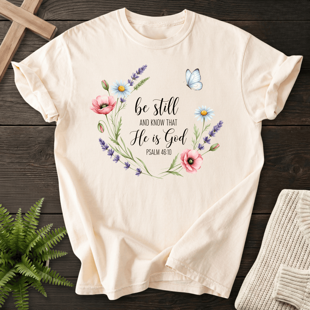 Ivory Christian t-shirt for women with a floral wreath of poppies, daisies, and a butterfly, inspired by Psalm 46:10.