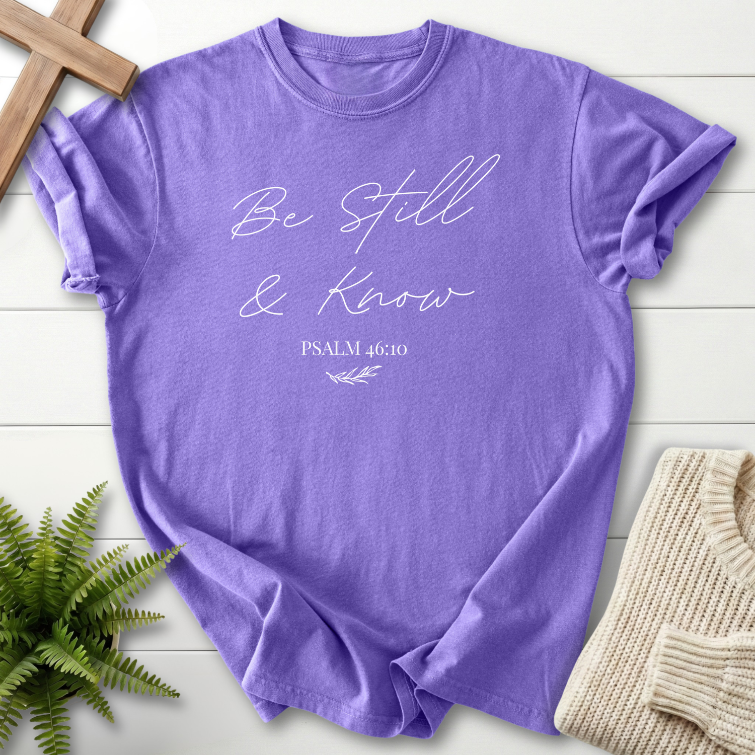 Violet garment-dyed Christian t-shirt for women with elegant gold 'Be Still and Know' Psalm 46:10 script