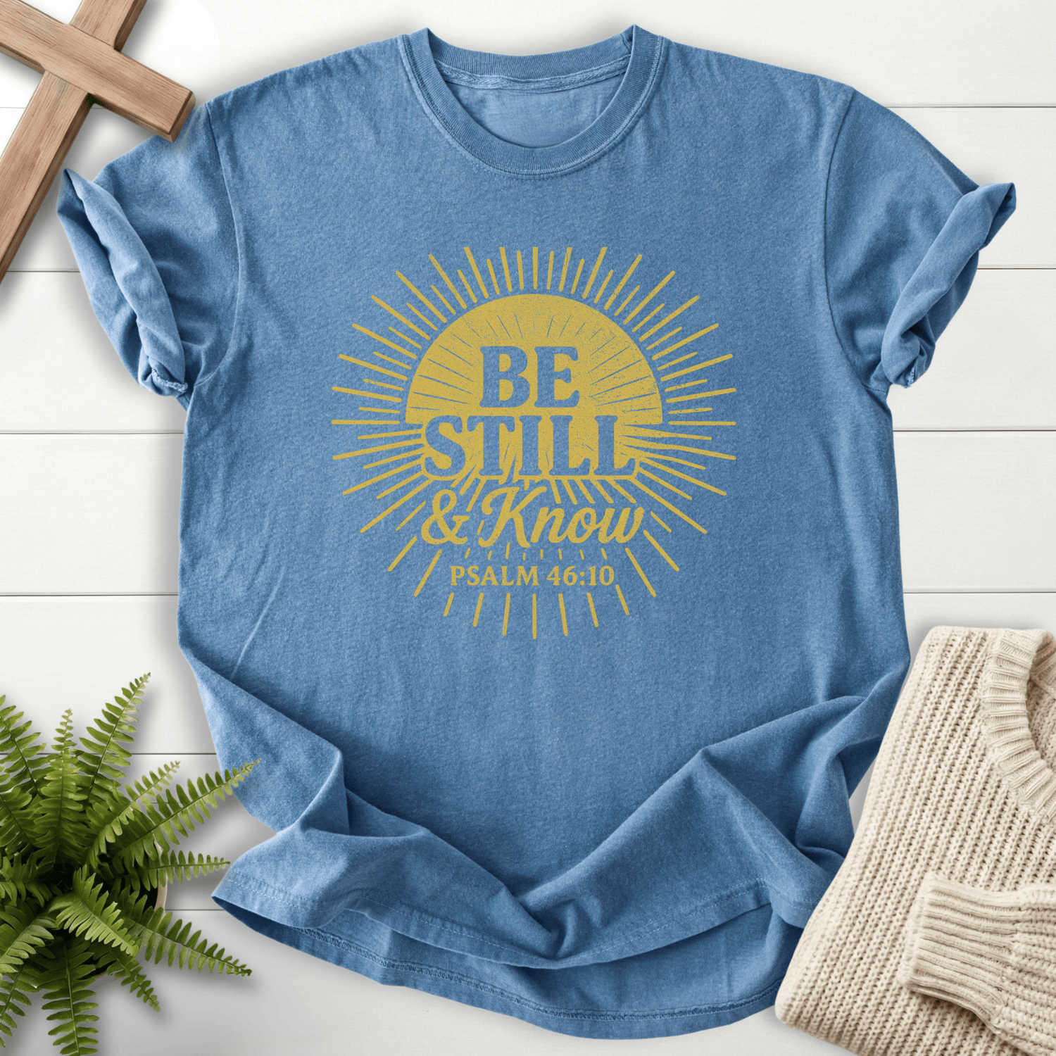 Blue Jean Christian t-shirt for women with a bold circular sunburst design and 'Be Still and Know', inspired by Psalm 46:10.