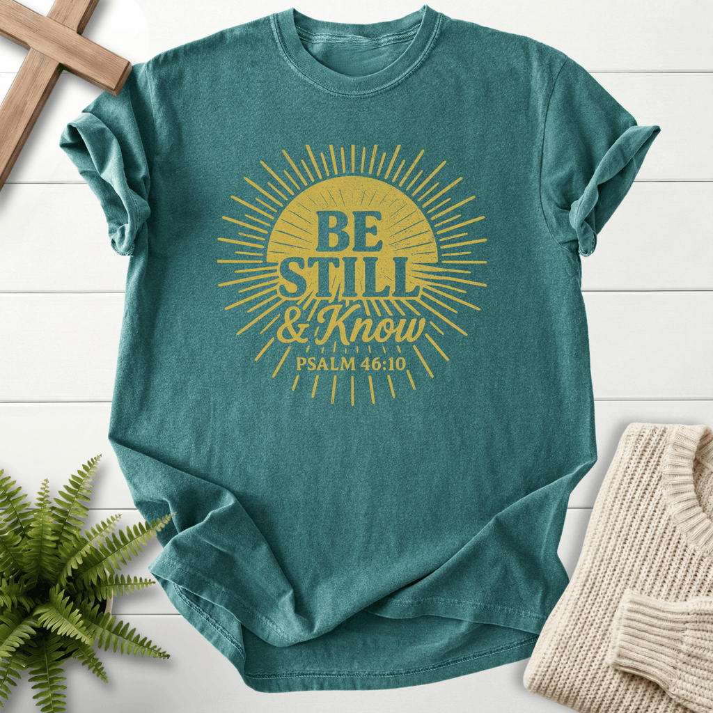 Blue Spruce Christian t-shirt for women with a bold gold sunburst graphic and 'Be Still and Know', inspired by Psalm 46:10.