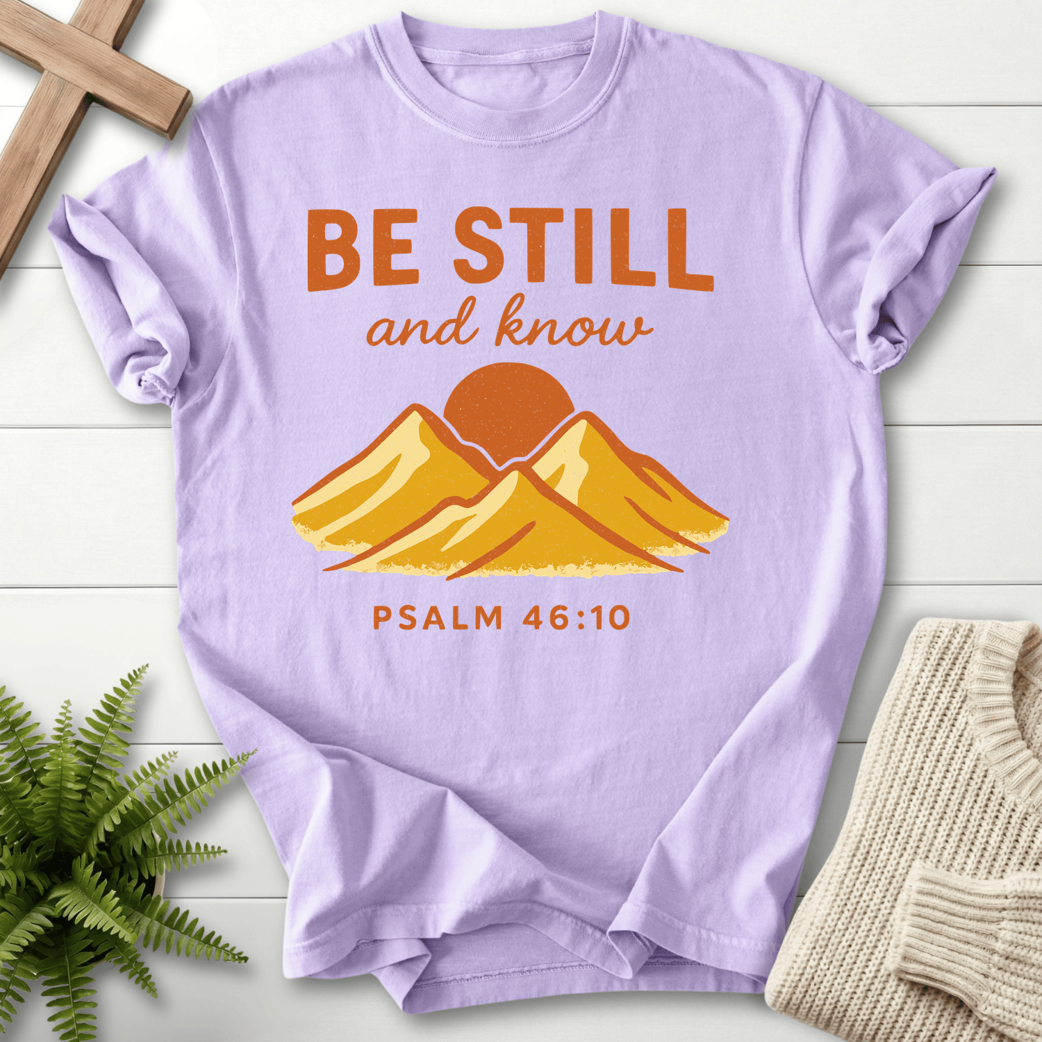 Orchid Christian t-shirt for women with a retro mountain and golden sunrise graphic, inspired by Psalm 46:10.