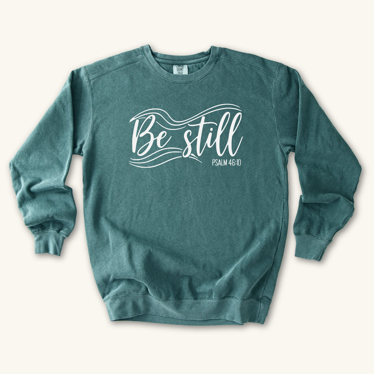 Blue Spruce Christian sweatshirt reading Be still in flowing brush script with sweeping lines, Psalm 46:10