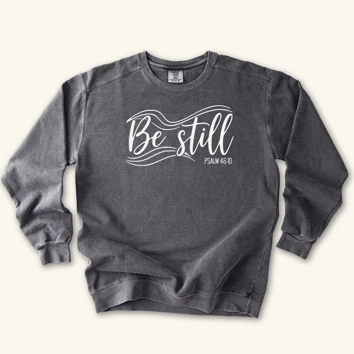 Pepper Christian sweatshirt reading Be still in flowing brush script with sweeping lines, Psalm 46:10