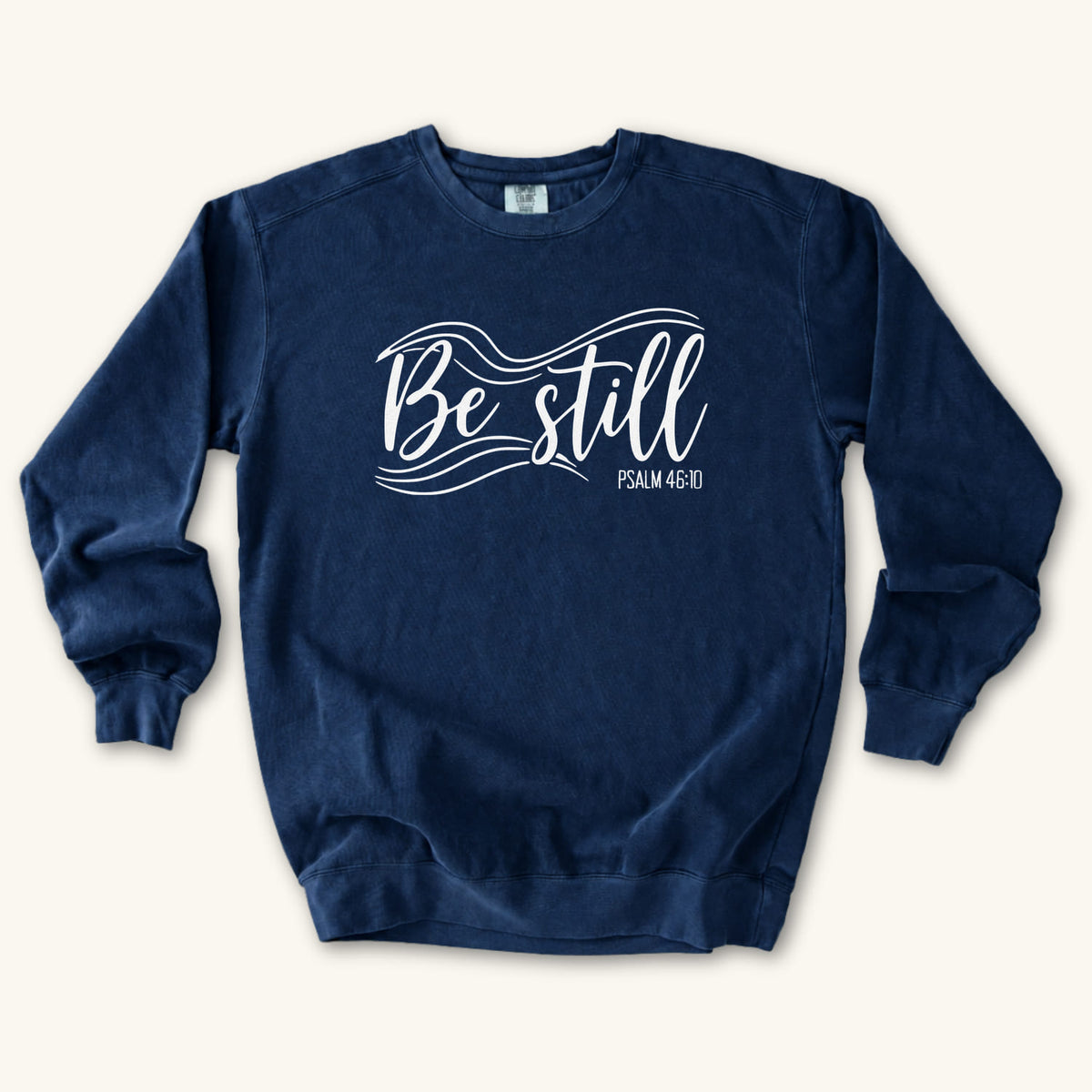 True Navy Christian sweatshirt reading Be still in flowing brush script with sweeping lines, Psalm 46:10