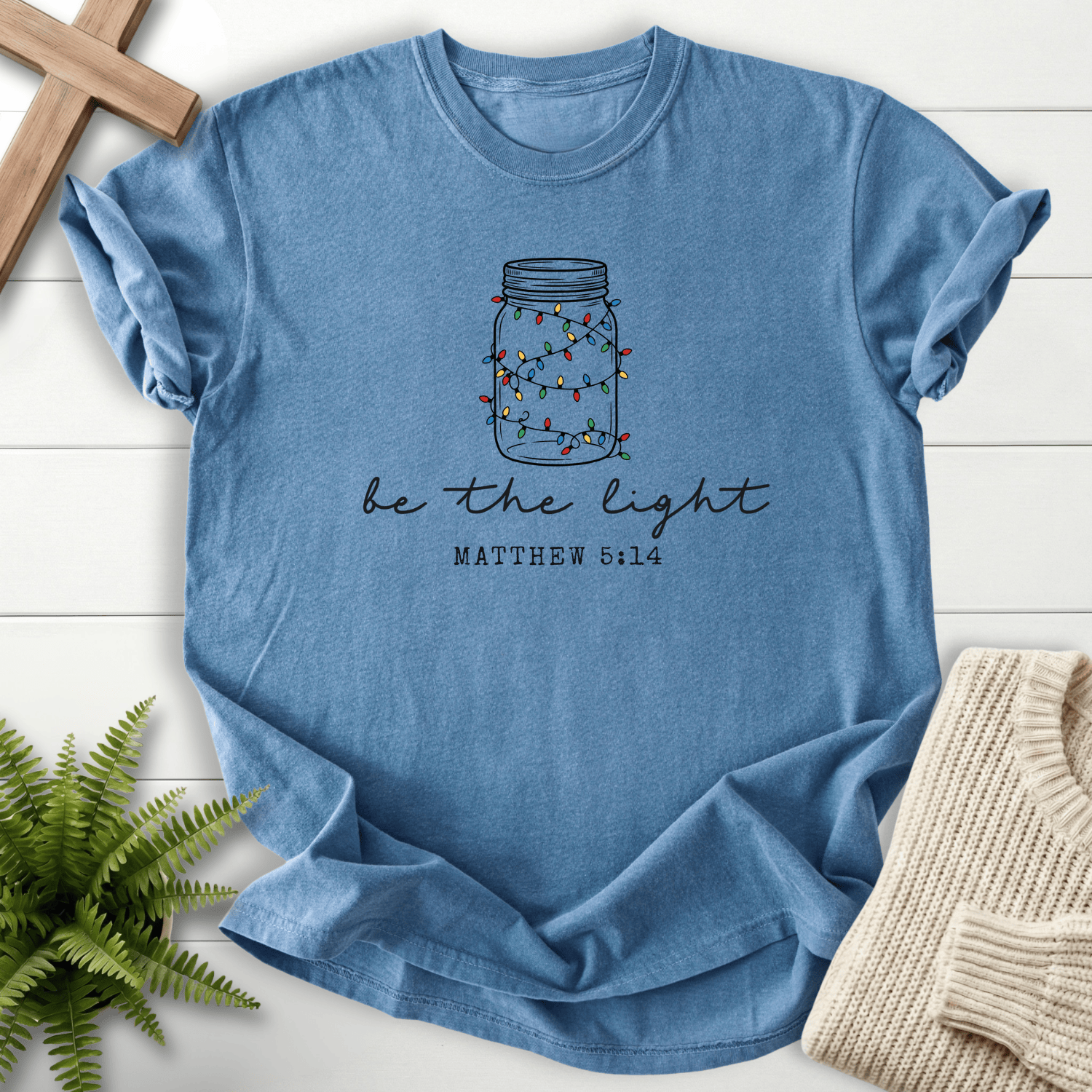 Blue Jean Christian t-shirt for women with a mason jar and colorful lights design and 'Be the Light', inspired by Matthew 5:14.
