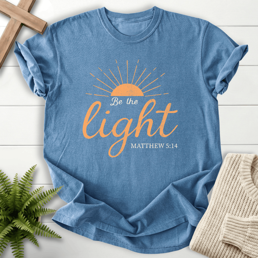 Blue Jean Christian t-shirt for women with a rising sun and script design, 'Be the Light', inspired by Matthew 5:14.