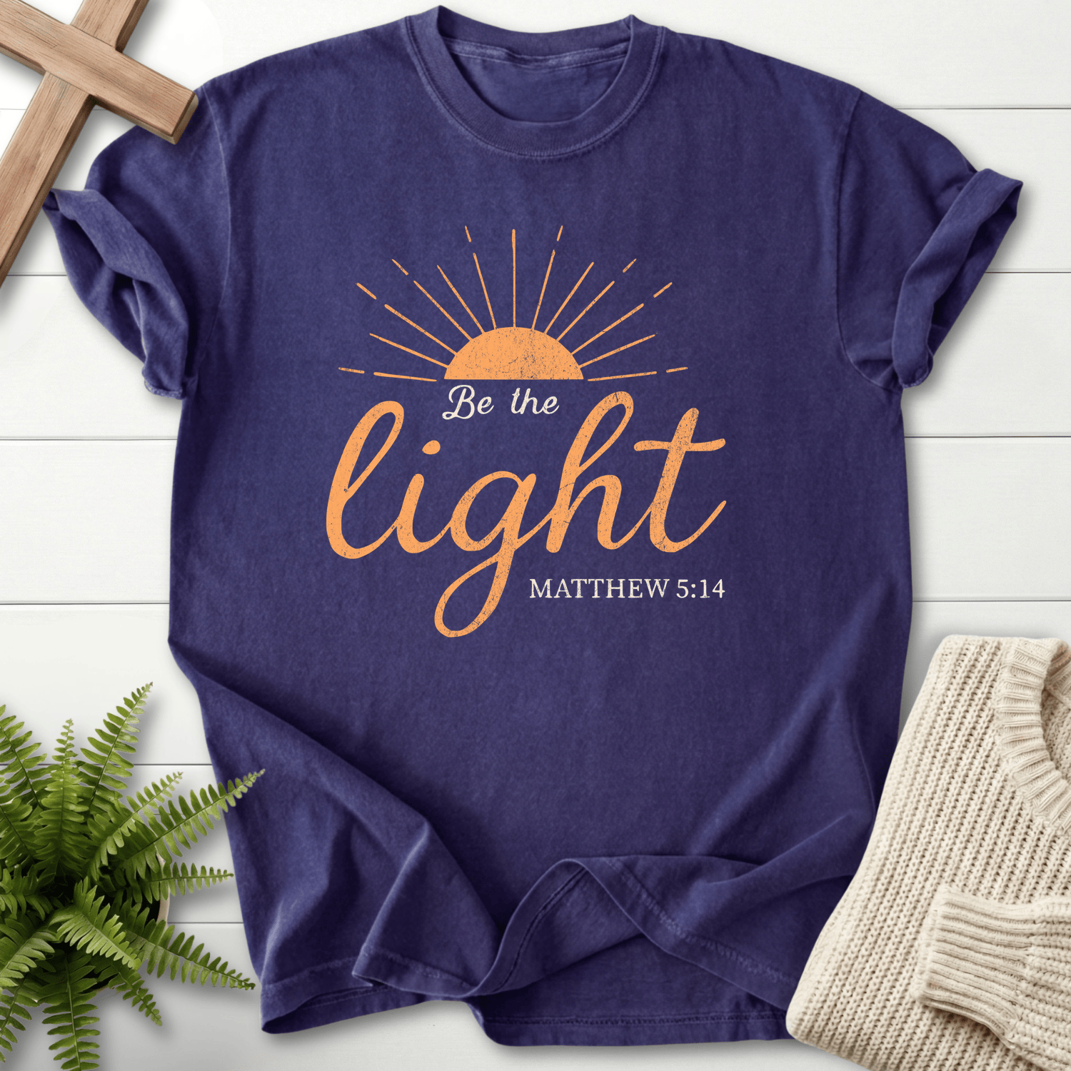 Grape Christian t-shirt for women with golden sunrise rays and elegant script design, 'Be the Light', inspired by Matthew 5:14.
