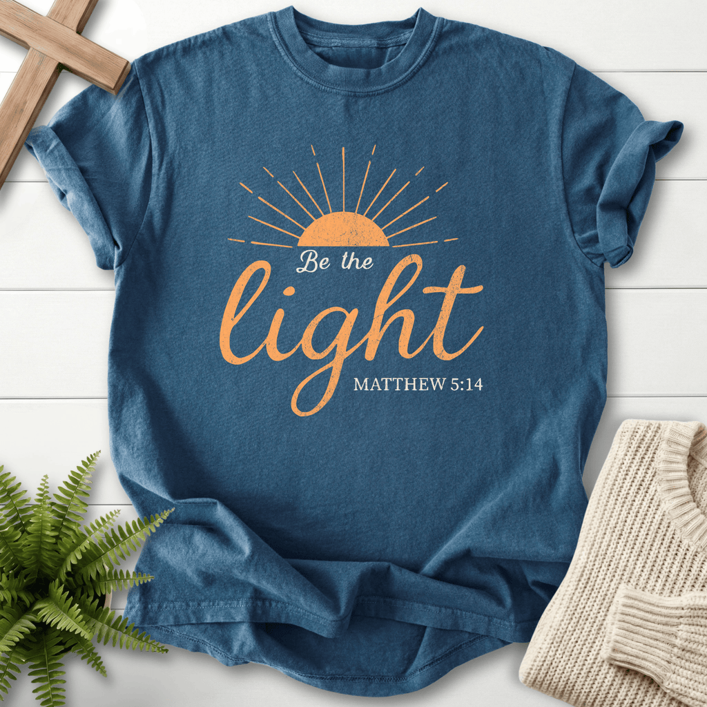 Midnight Christian t-shirt for women with a half-sun sunrise illustration and warm gold script, 'Be the Light', inspired by Matthew 5:14.