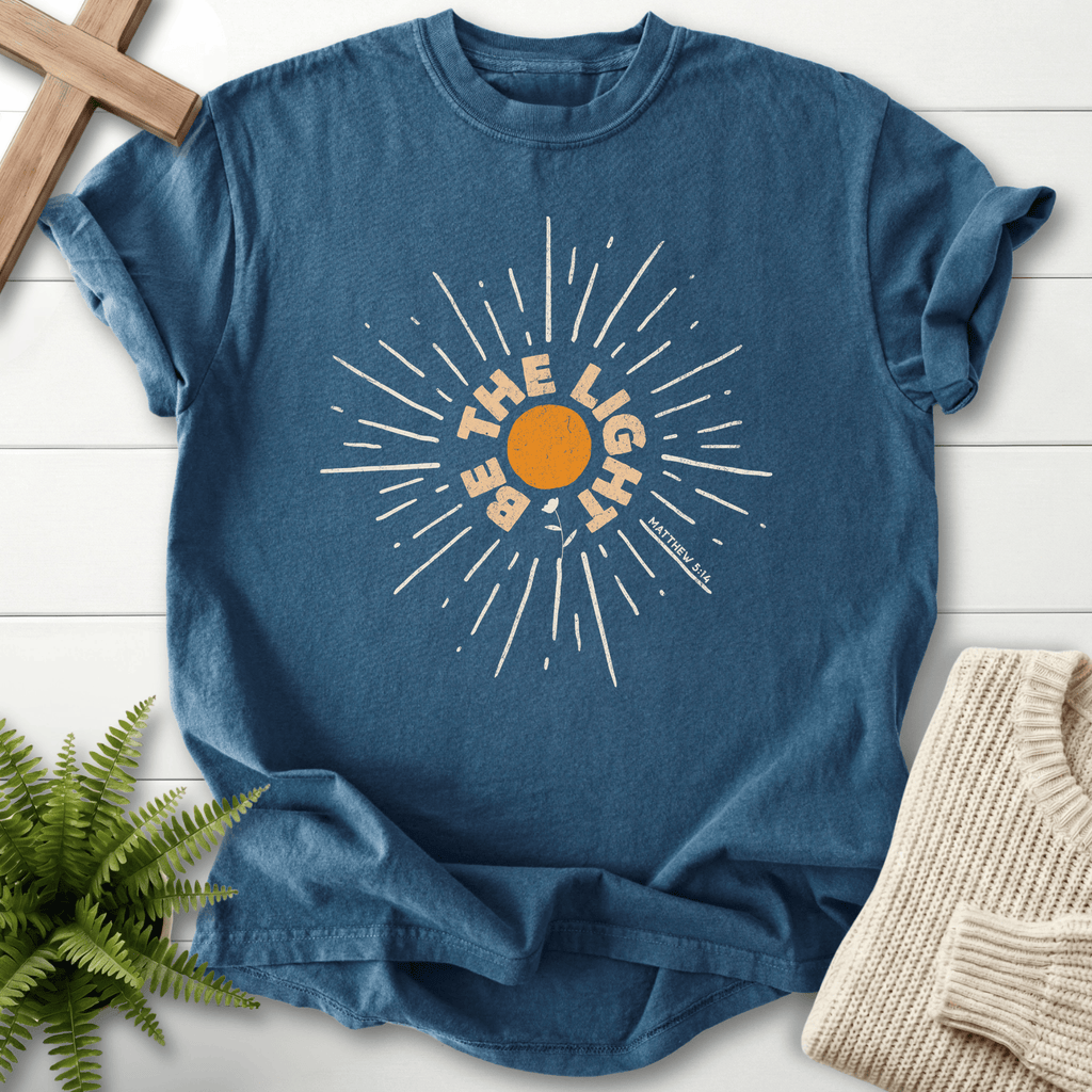Midnight Christian t-shirt for women with a bold circular sunburst graphic and 'Be the Light', inspired by Matthew 5:14.