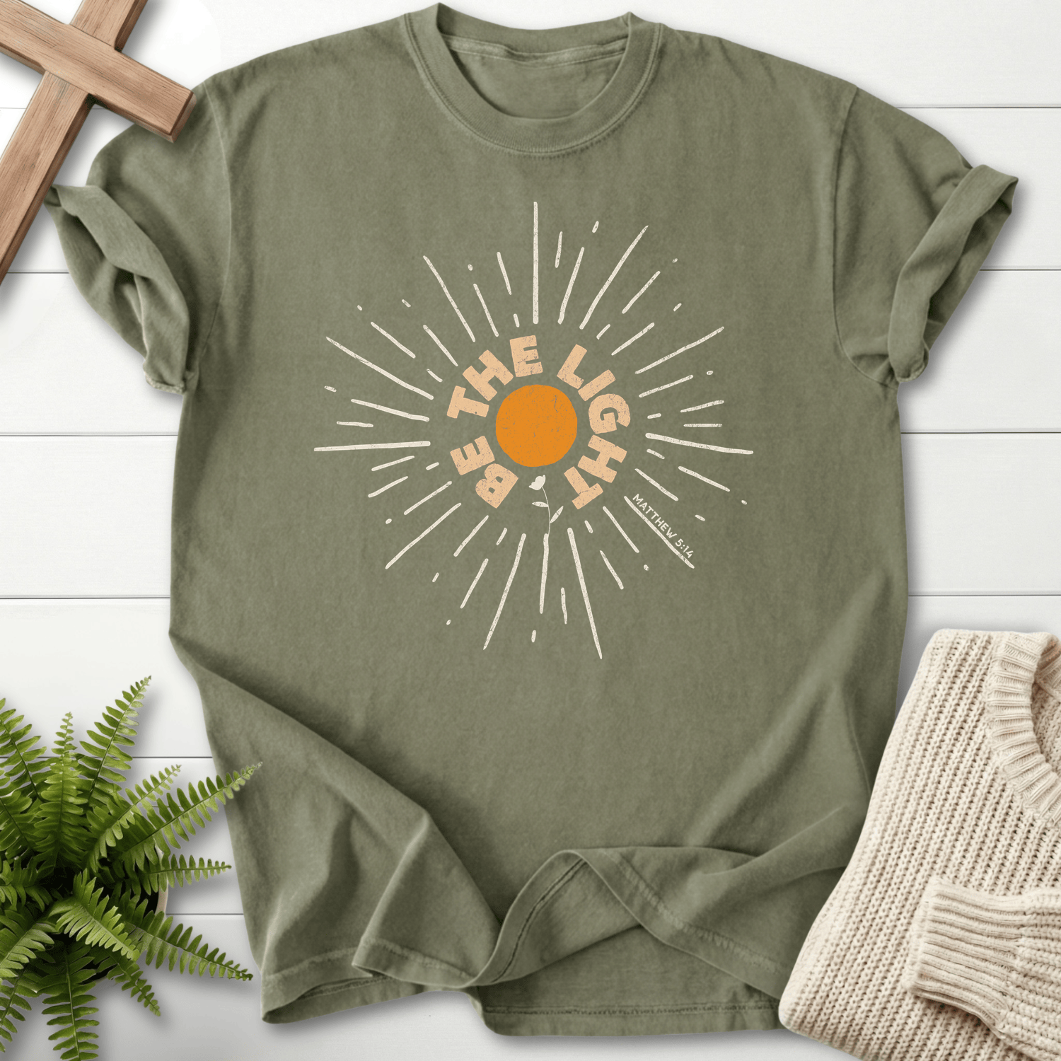 Sage Christian t-shirt for women with a bold circular sunburst and 'Be the Light', inspired by Matthew 5:14.