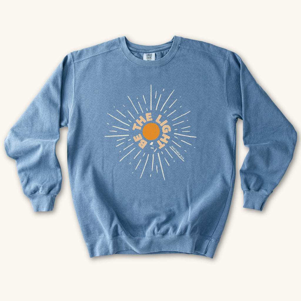 Blue Jean Be The Light Sunburst sweatshirt flat lay mockup, Matthew 5:14 Christian apparel for women