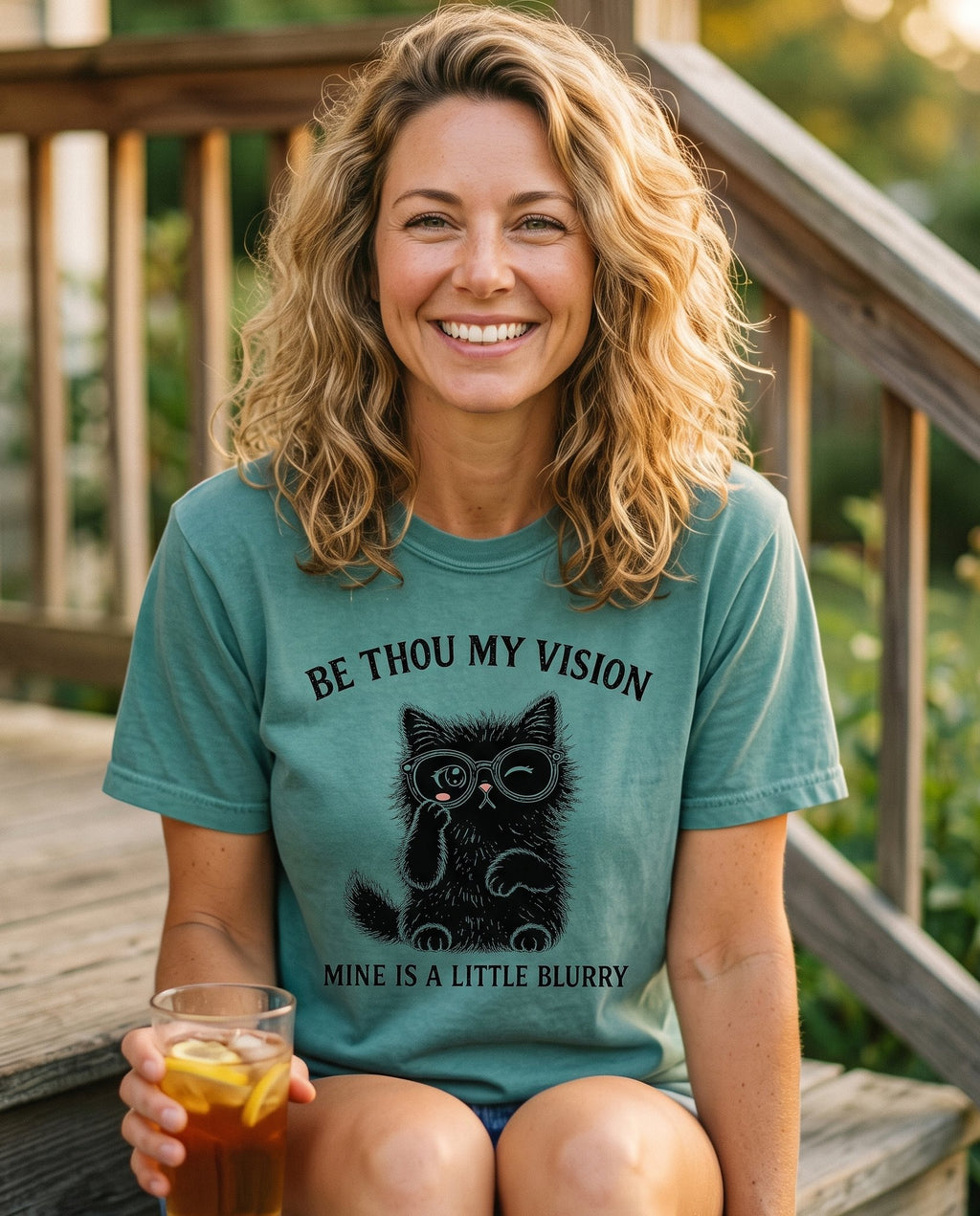 Be Thou My Vision Cat – Chalky Mint women's Christian tee, lifestyle photo in sunny porch – A winking black kitten in round glasses with one paw raised beneath th – Be Thou My Vision (hymn) – She Wears Faith